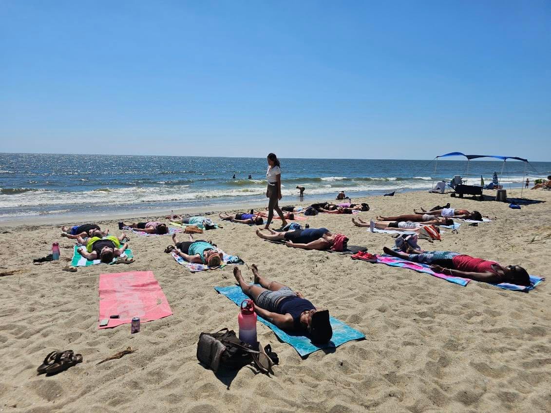 Participants resting in savasana on towels along the shoreline